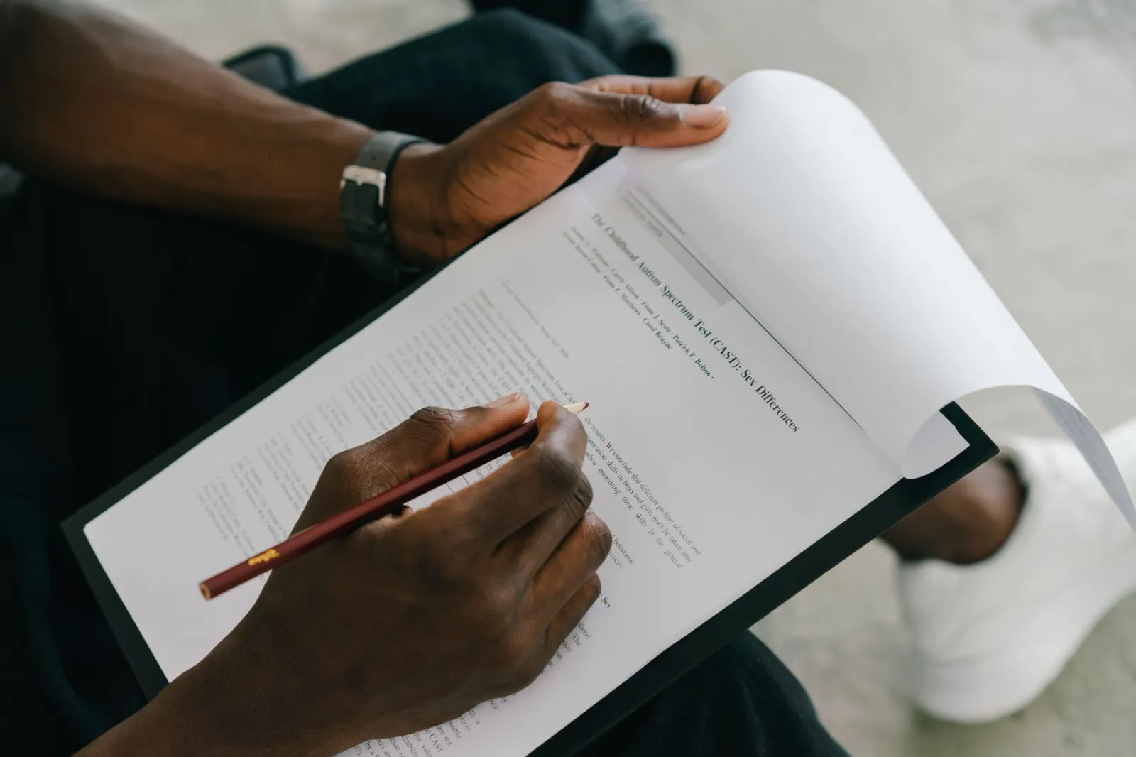 Close-up of a person writing on a psychological assessment form with a pencil.