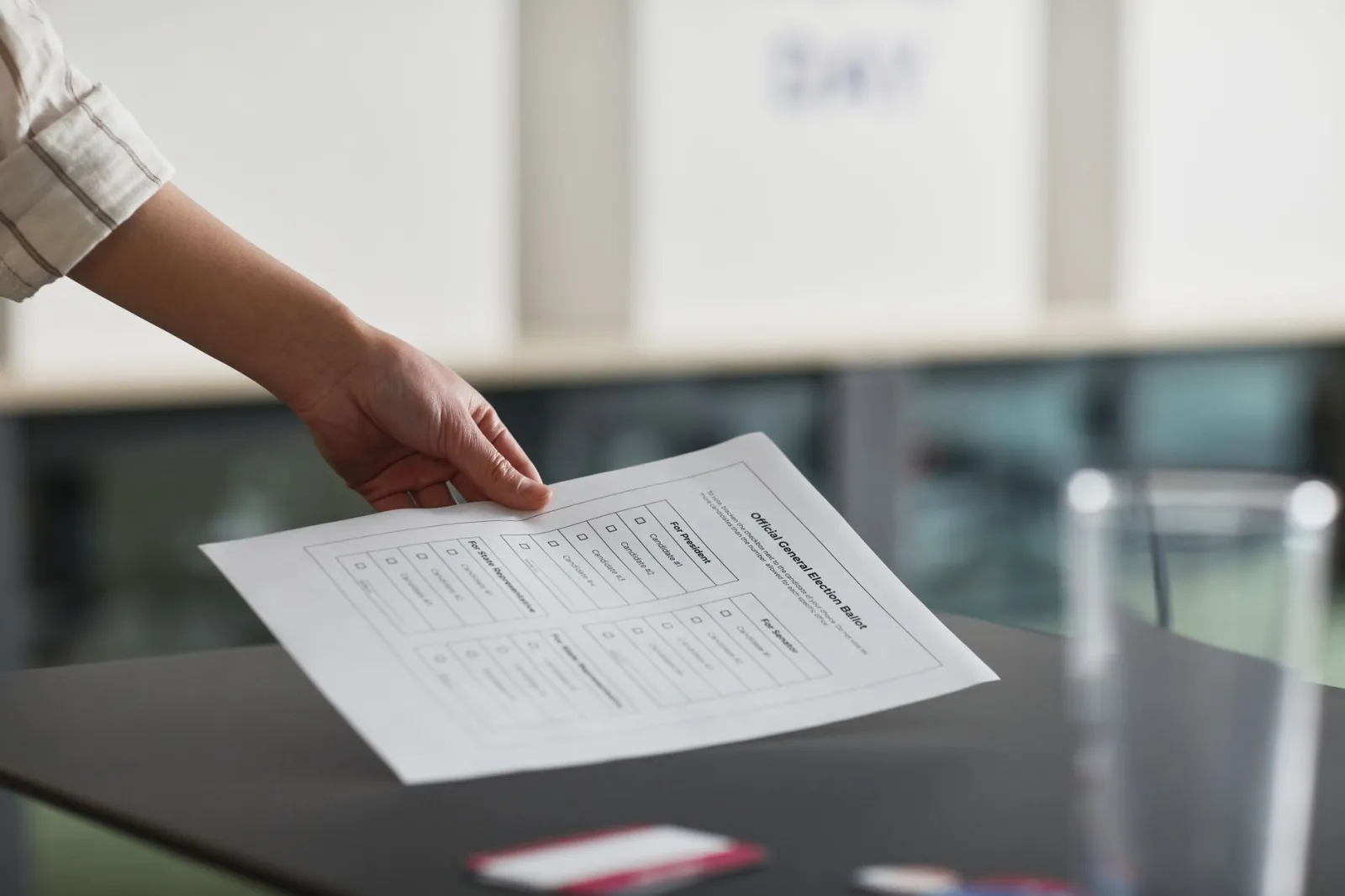 Close-up of a hand holding a ballot paper indoors, symbolizing democracy and civil rights.